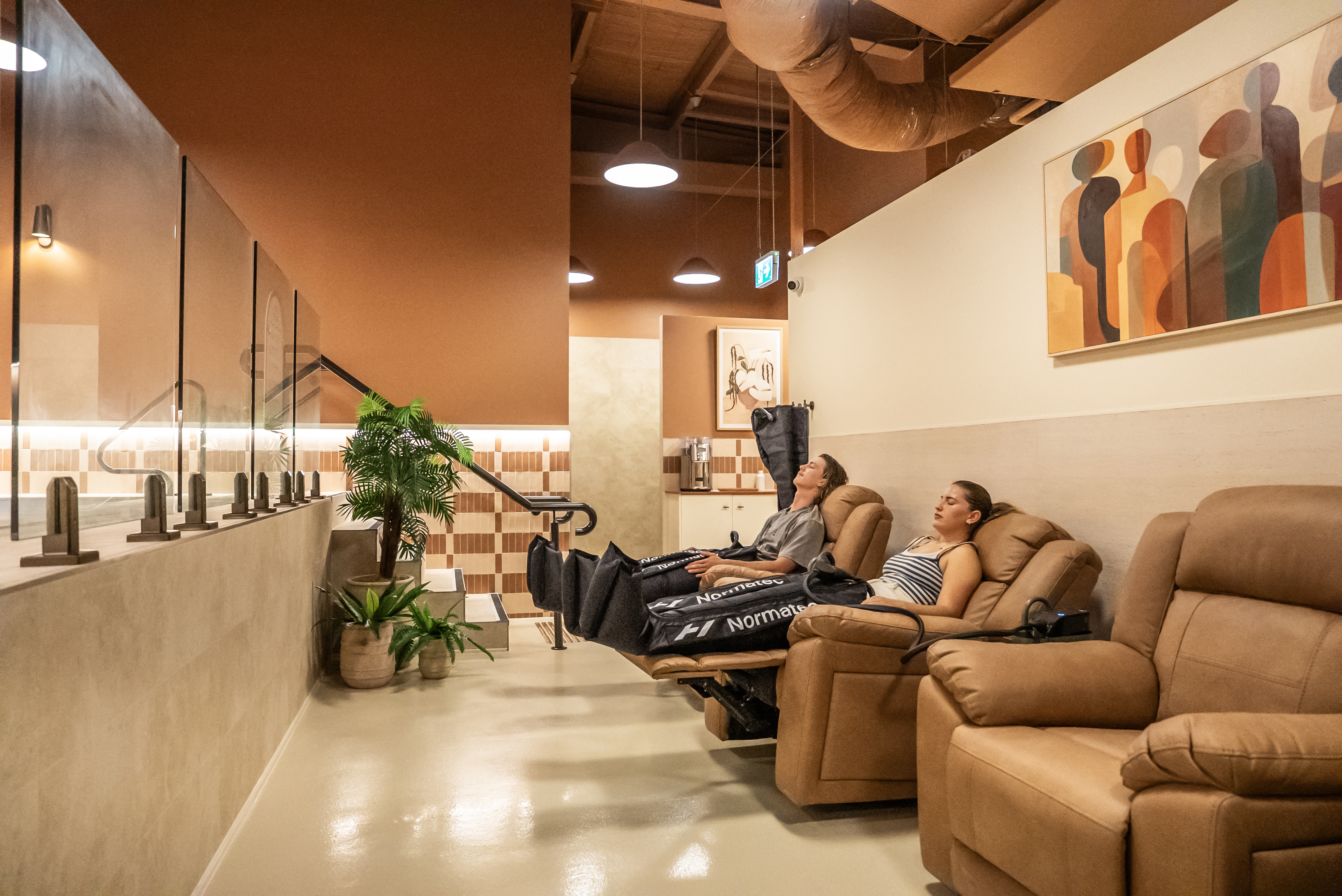 Guests relaxing with Normatec compression boots at Square Recovery Noosa